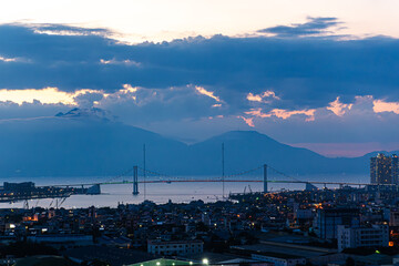 Twilight view of Da Nang, Vietnam, featuring a bridge and the bay with mountains in the background....