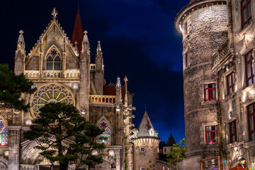 A beautifully illuminated cathedral and surrounding buildings at night. The Gothic architecture and...