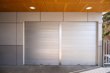 Two closed and locked metallic roller shutter doors of a shop or a small convenience store,...