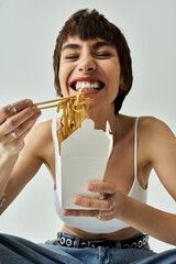 A stylish young woman gracefully enjoying noodles with chopsticks.