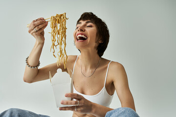 A beautiful young woman in stylish attire sitting on the floor, eating noodles.