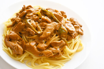 Chicken curry spaghetti on fork in a bowl. Italian and Indian mixed dishes. Fusion food.