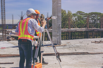 Engineer or surveyor worker working with theodolite transit equipment at outdoors construction site.