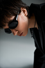 A woman in black sunglasses leaning against a wall.