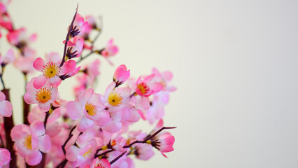 A bouquet of plum blossoms in glass vase, pink artificial flowers, interior decor, copy space.