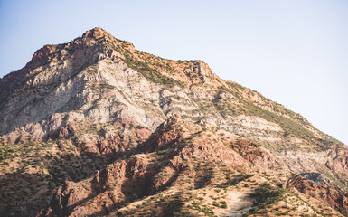 Texture of a rocky mountain range with rocky cliffs and vegetation in the morning at dawn in the mountains of Tajikistan