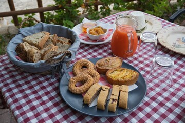 Breakfast served outside on a table with a red checkered tablecloth. Breakfast in the countryside. 