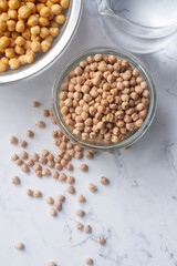 Dried chickpea in a glass bowl on white marble background.