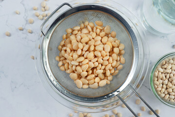 navy beans in a strainer after being soaked in water.