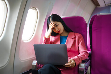 A young Asian female airplane passenger sits by the window during the flight, experiencing nausea...