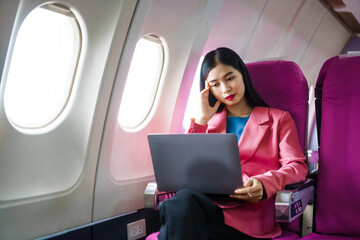 A young Asian female airplane passenger sits by the window during the flight, experiencing nausea...