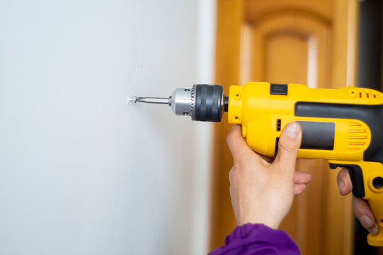 close-up of a man drilling a wall,