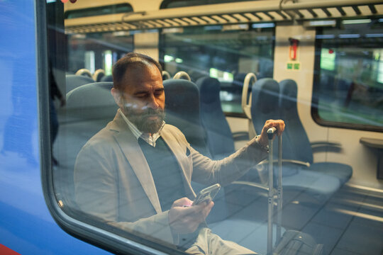 Mature businessman using smartphone on a train
