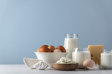 Eggs, milk, yogurt, cottage cheese, cheese side view on blue background. Dairy farm products concept