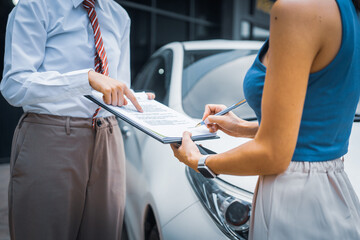 A young businesswoman is navigating car insurance options at her desk, considering premiums,...