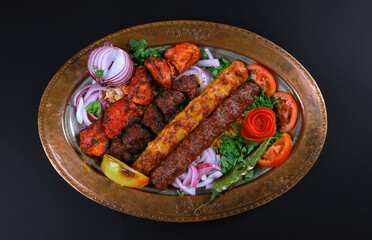 platter with mixed kebab grilled meat vegetable on brass plate black background 