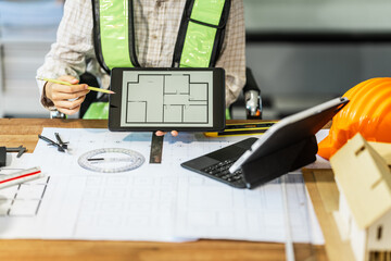 Female architect engineer is drafting blueprints using CAD software, focusing on sustainable...