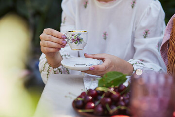 Woman holds vintage tea cup in peaceful, pastoral ambiance. Sustainable living, femininity, and the elegance of rural life