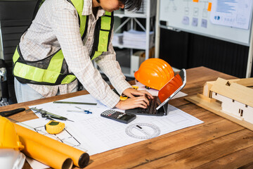 Female architect engineer is drafting blueprints using CAD software, focusing on sustainable...