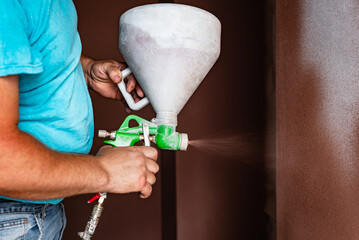 Applying a primer to the wall using spray gun.