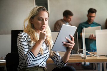 Confident and successful. Confident young woman in startup business office holding digital tablet