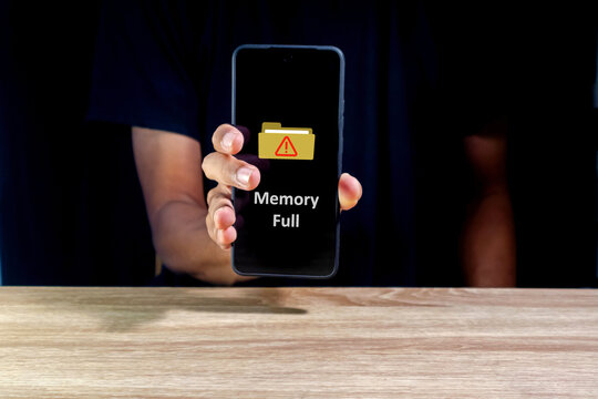 Man holding a smart phone with memory space full notification on screen