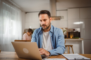 Adult man work form home on laptop with son at background