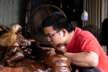 Obraz premium Side view of a Vietnamese man with eyeglasses working in a wood craft workshop