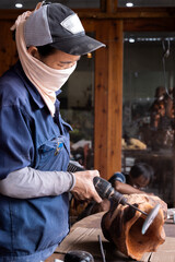 Fototapeta premium Vertical photo of a woman with her face covered working in a wood workshop.