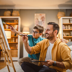 Father teach mentor son to create art at home on easel with brush