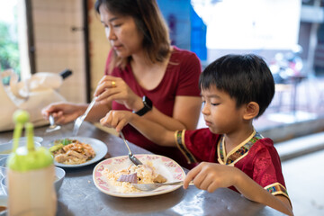 Little asian boy with mom eat steam rice in street food local city Yaowarat