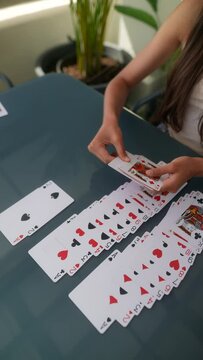 A woman is playing solitaire outdoors on a patio table