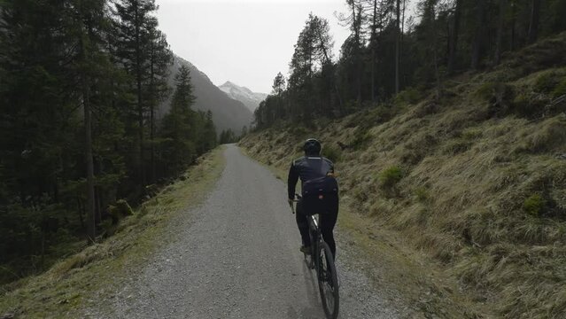 Man cyclist rides gravel bike in spring along beautiful large mountain lake Plansee in Austria. Male bicyclist cycling through Am Plansee cycleway in Osterreich. Cycling tours in Austria. 