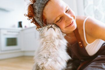 Portrait red-haired curly young woman with beloved fluffy domestic cat
