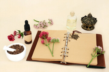Valerian adaptogen herb root with flowers, notebook and essential oil bottles. Used in herbal...