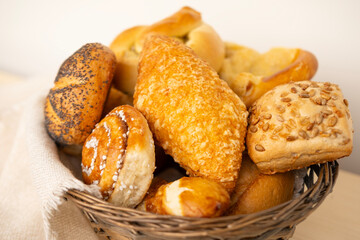 wicker basket overflowing with freshly baked pastries: cheese and poppy seed buns, pretzels, and sweet curd tarts
