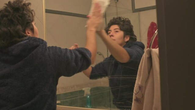 Limpiando el espejo de un ba&ntilde;o de casa con una servilleta