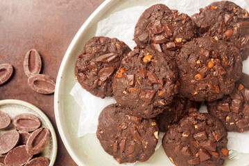 double chocolate cookies in ceramic plate on rusty background.