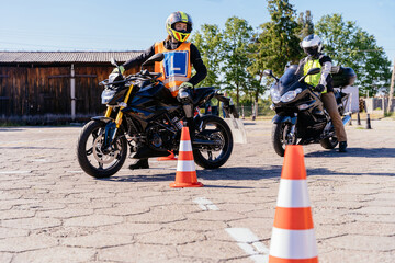 Motorcycle driving school concept. Charming woman in orange vest with Letter L sign