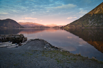 Fototapeta premium Norwegian landscape. View over a small harbor to the fjord at sunset behind the mountain