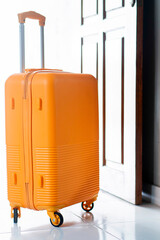 Yellow hard-shell suitcase near a wooden door