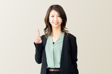 人差し指を立てて案内する笑顔の女性・ビジネスウーマン