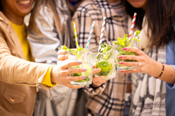 Group of friends clinking their colorful cocktails at an outdoor party, enjoying a fun day together.