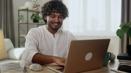 Handsome freelancer working on laptop checking email surfing web indoors Concentrated young indian man student has online distance education on computer and looking at screen at home workplace