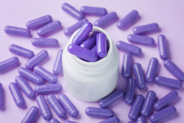 Sleeping pill concept with pile of purple capsules in bottle