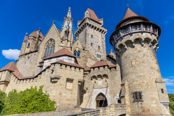 Fototapeta premium Castle landmark under blue sky. Medieval castle in Austria. Ancient historical sights around Vienna. Castle Kreuzenstein old building from outside