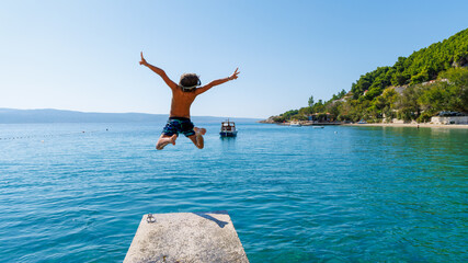 Happy boy jumping into the sea- Summer vacation, travel