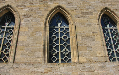 windows with wrought iron bars of an old stone gothic style building