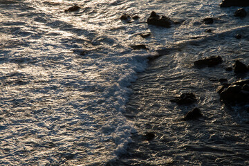 View of the surf on the rocky seaside after sunrise