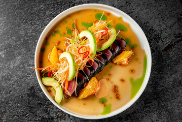 tuna tataki with vegetables and sauce on white plate